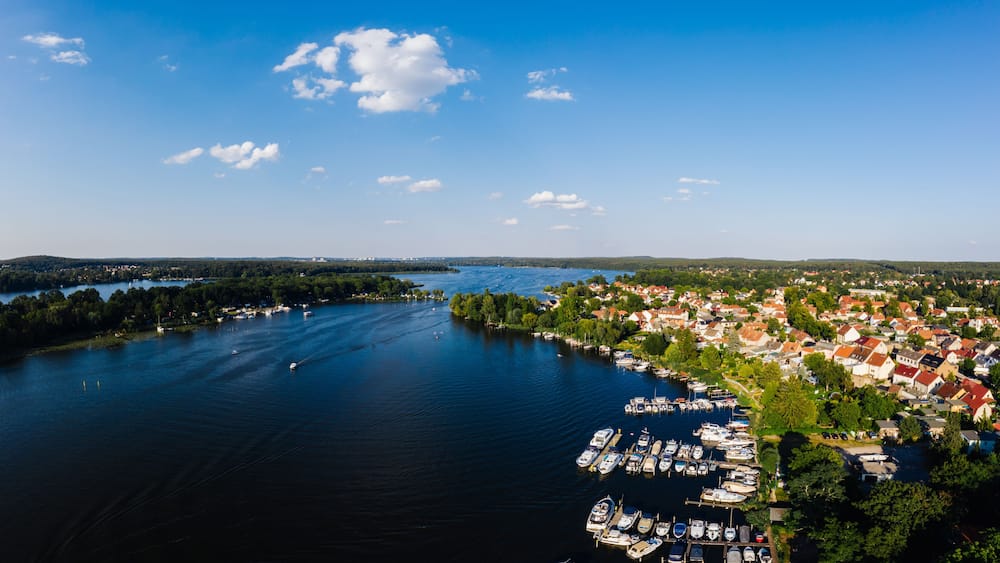 A lake surrounded by a town with boats docked along the shore.