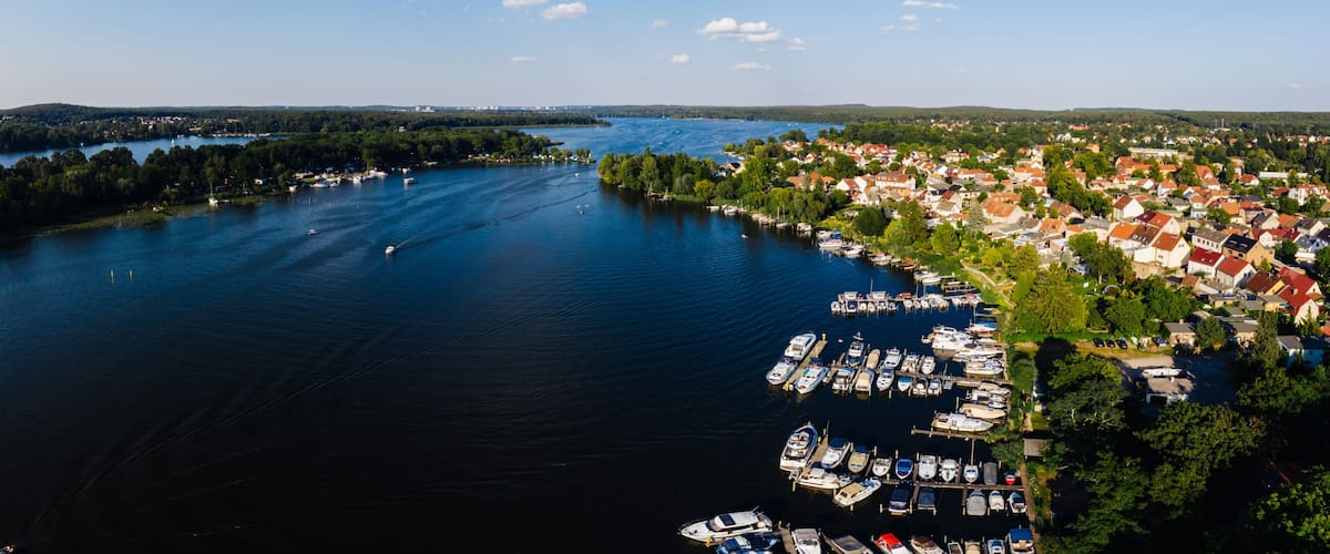 A lake surrounded by a town with boats docked along the shore.