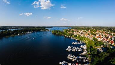 A lake surrounded by a town with boats docked along the shore.