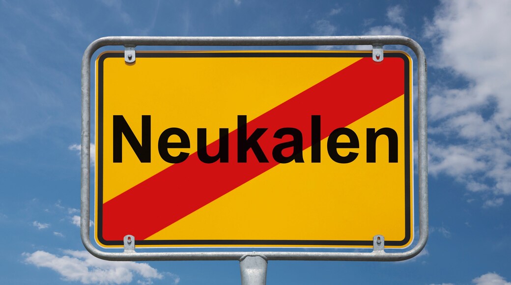 Placa de rua com a palavra 'Neukalen' sob um céu azul com nuvens.