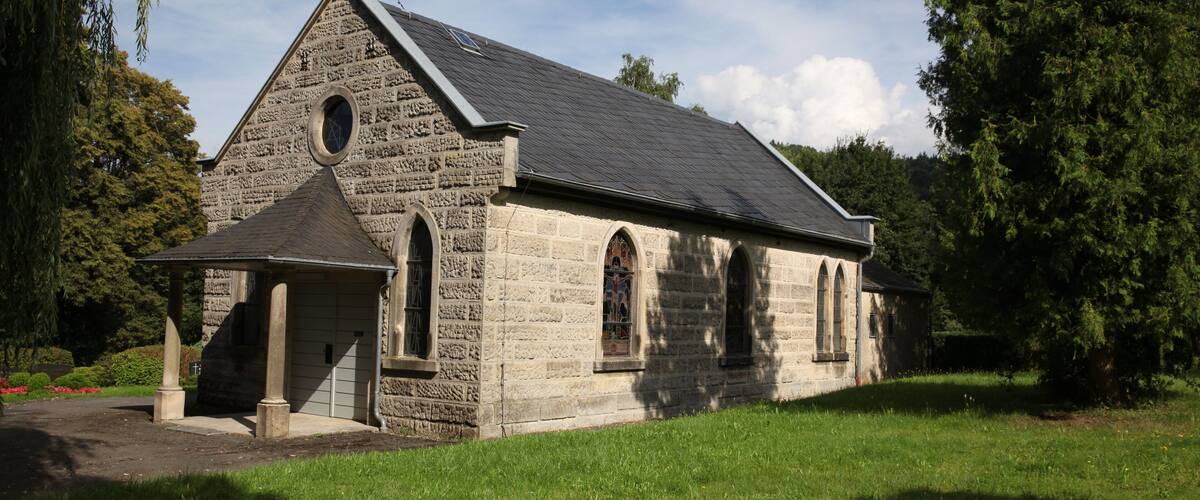 A stone church with a steep gable roof and a cross on top.
