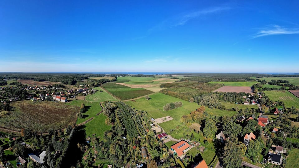 A rural landscape with fields, a small village, and a clear blue sky.