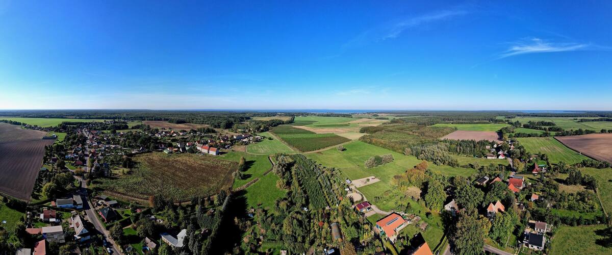 A rural landscape with fields, a small village, and a clear blue sky.