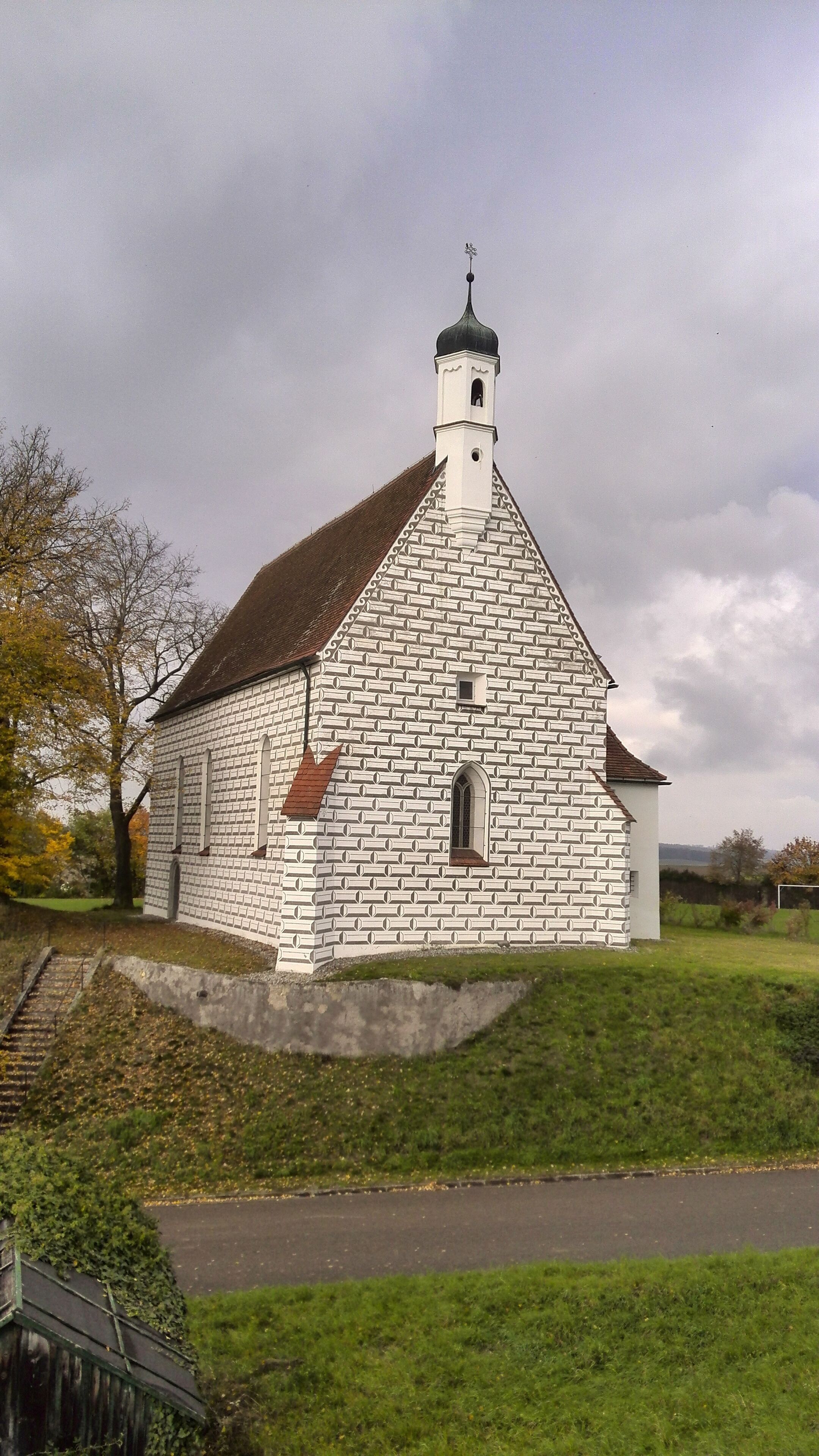 A white church with a brick pattern, a bell tower, and a steep roof.