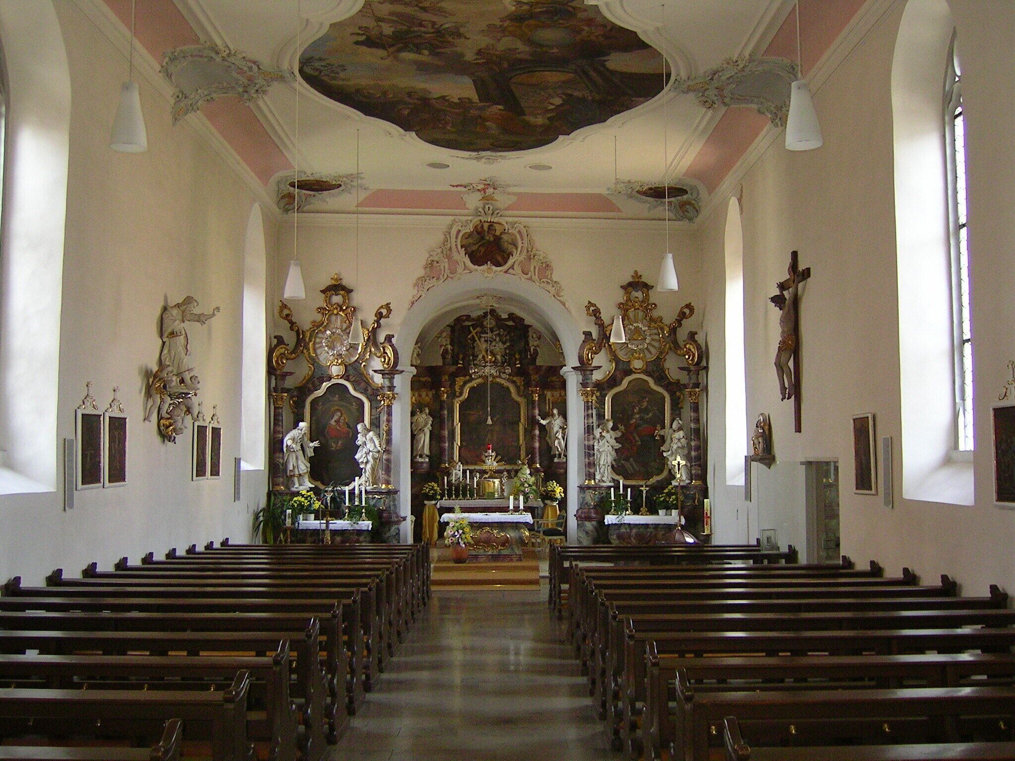 An ornate church interior with wooden pews, a crucifix, and a large altar.