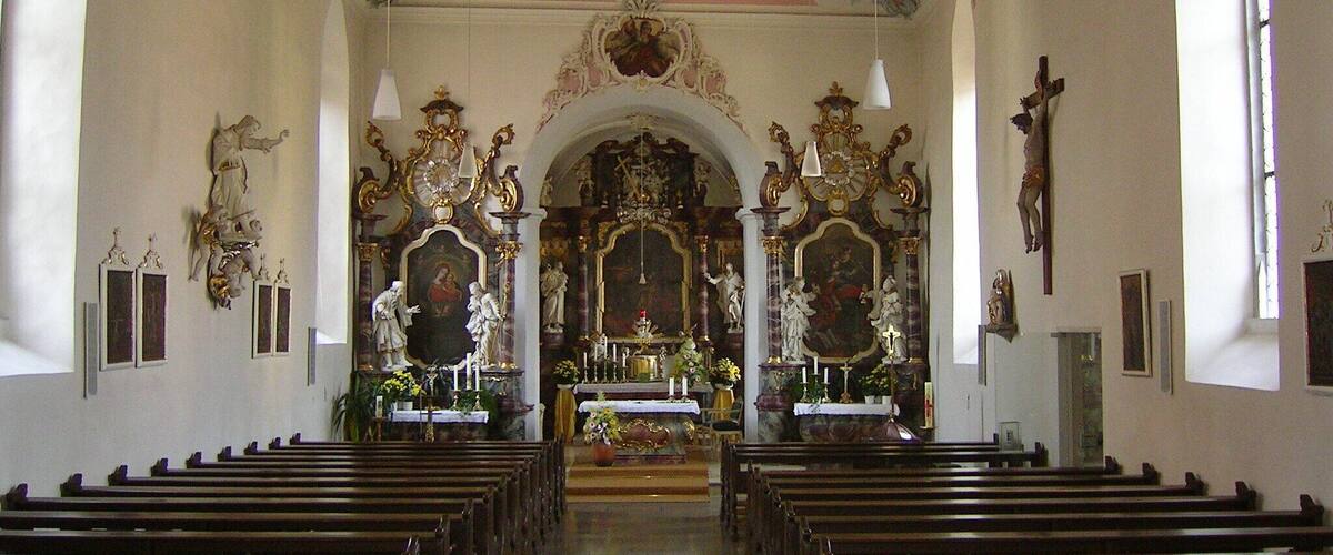 An ornate church interior with wooden pews, a crucifix, and a large altar.