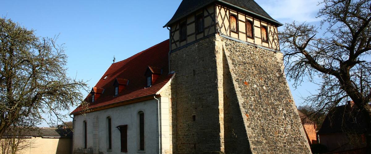 A historic building with a stone tower and a red-tiled roof.