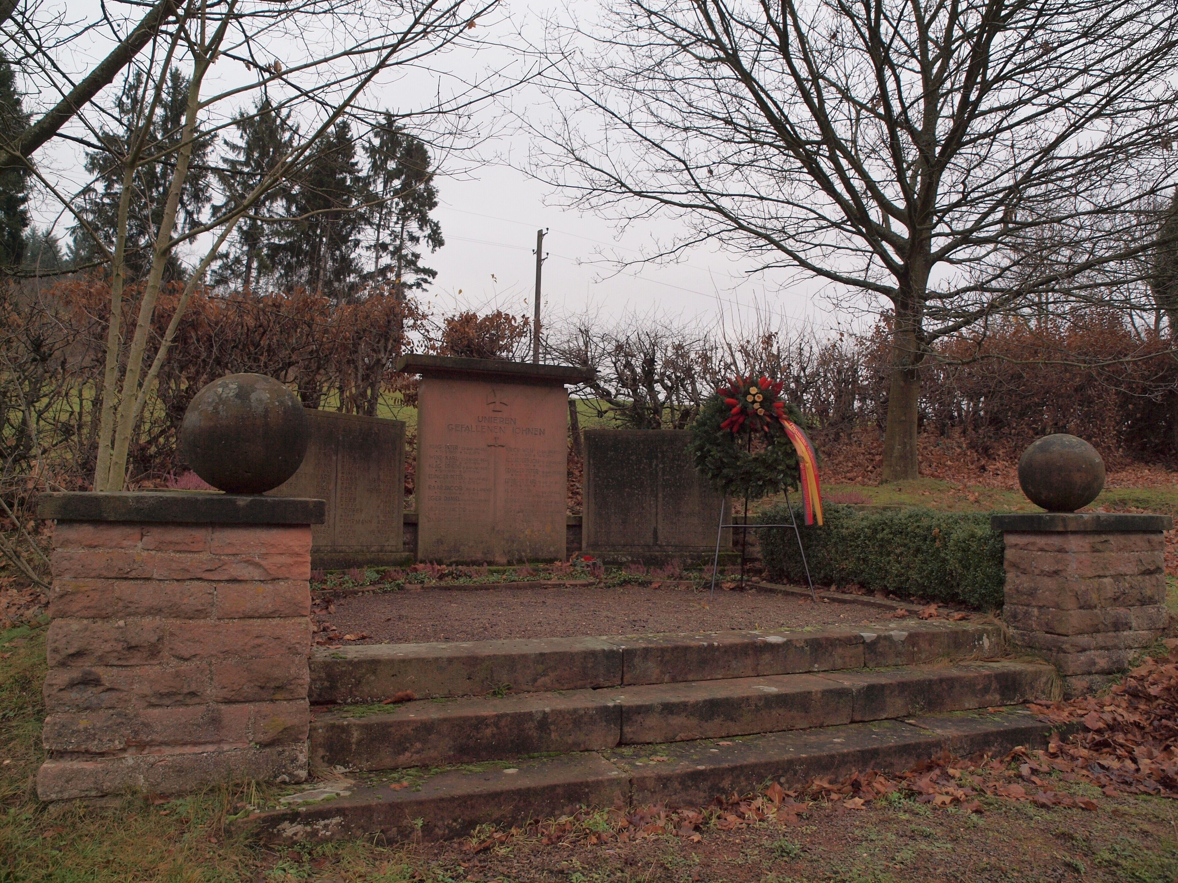 A cemetery with stone walls, a memorial, and a Christmas tree.
