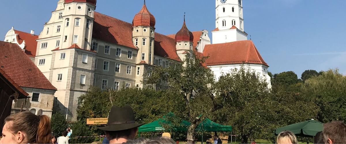 A historic building with multiple towers and domes, surrounded by trees and people.