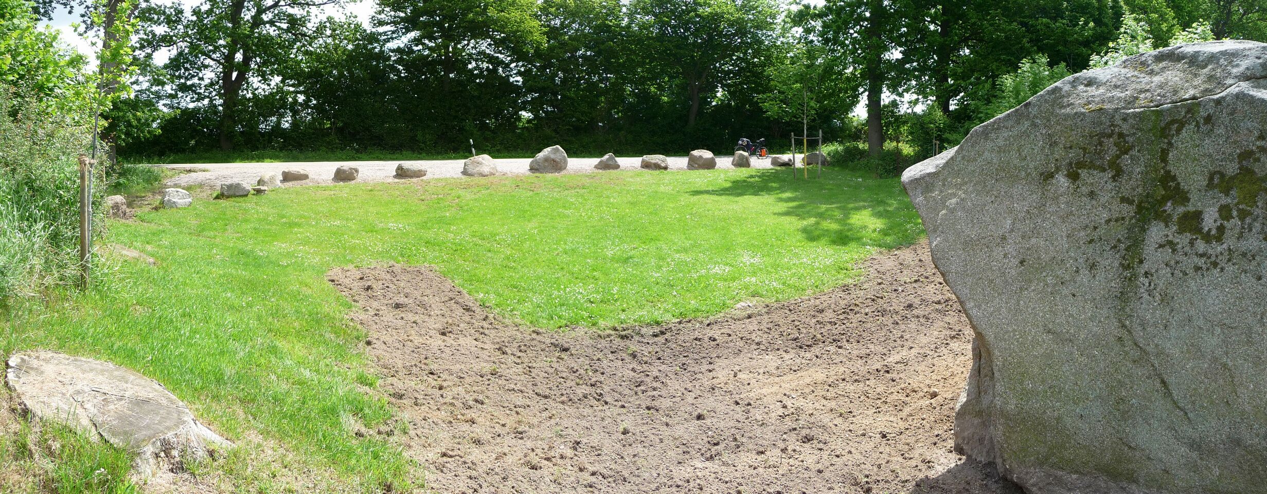 A grassy area with large rocks and a dirt patch.