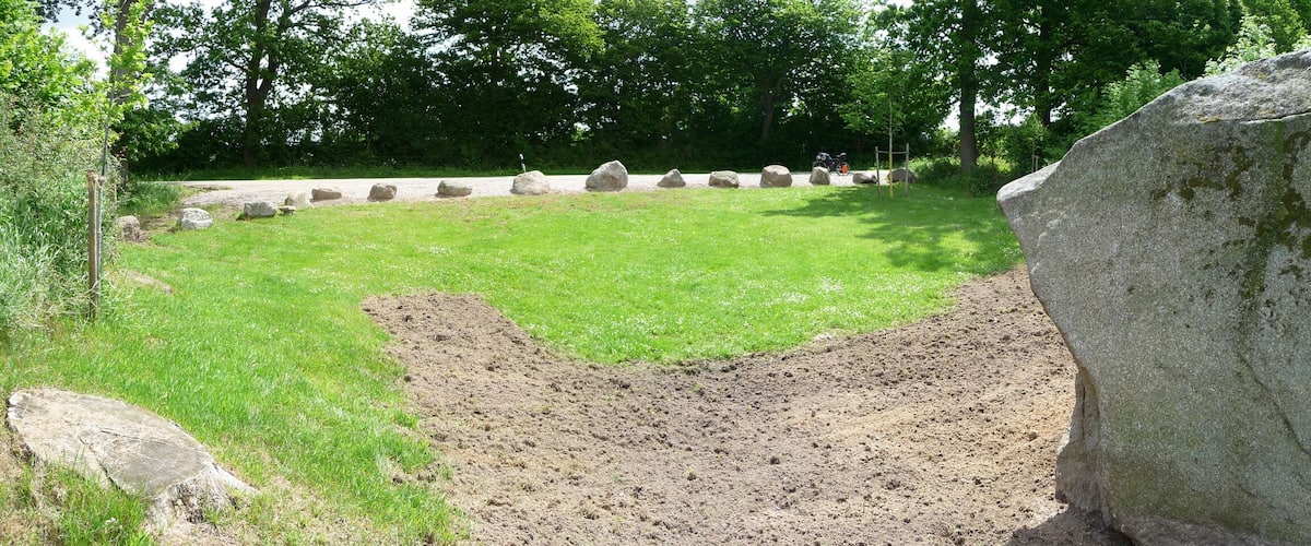 A grassy area with large rocks and a dirt patch.