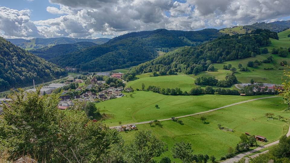 A valley with green fields, a small village, and rolling hills.