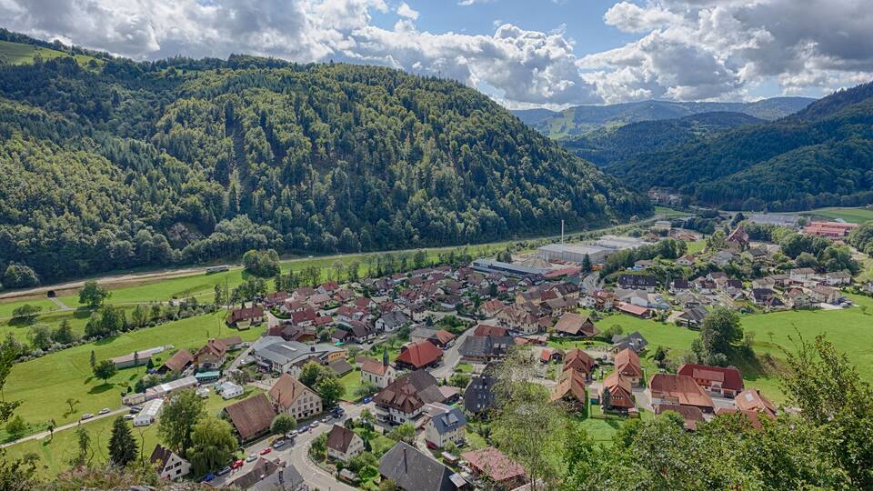 A village nestled in a valley surrounded by forested hills.