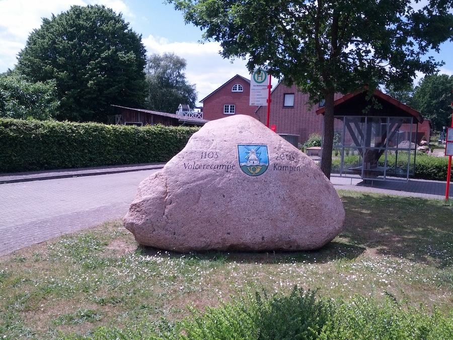 Una gran piedra con un escudo de armas e inscripciones que marcan un lugar histórico.