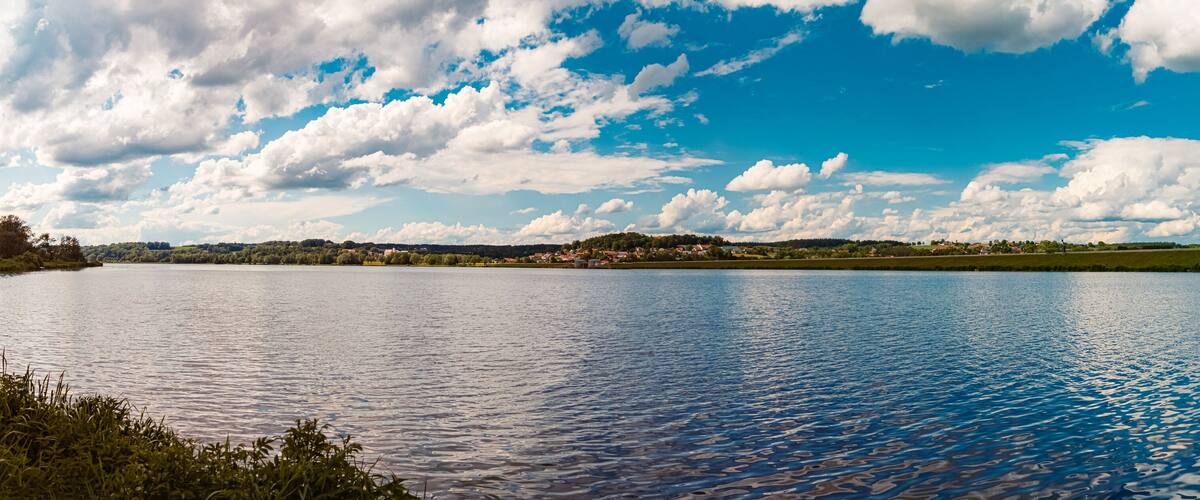 A lake with a clear sky and scattered clouds.