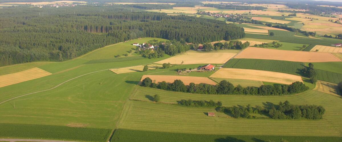 An aerial view of a rural landscape with fields, forests, and scattered houses.