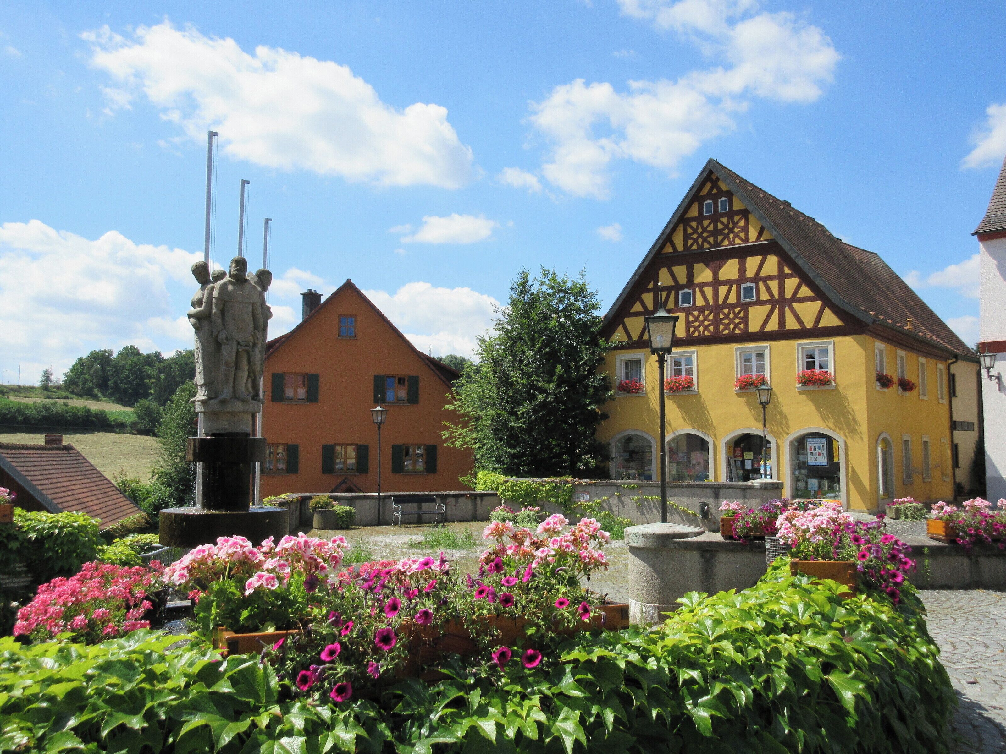 A traditional half-timbered house with a statue in front.