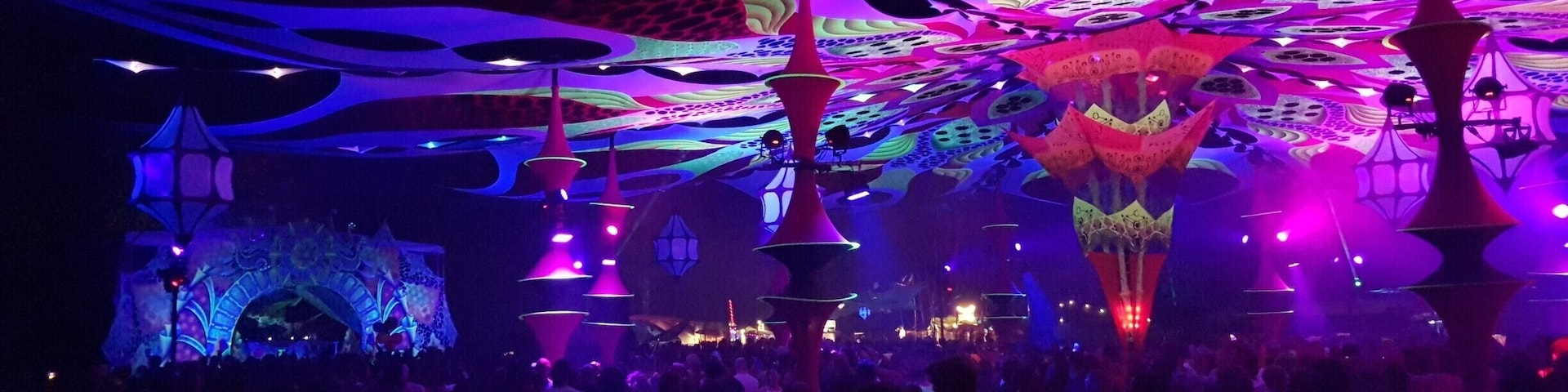 A vibrant indoor venue with colorful lighting and abstract ceiling designs.