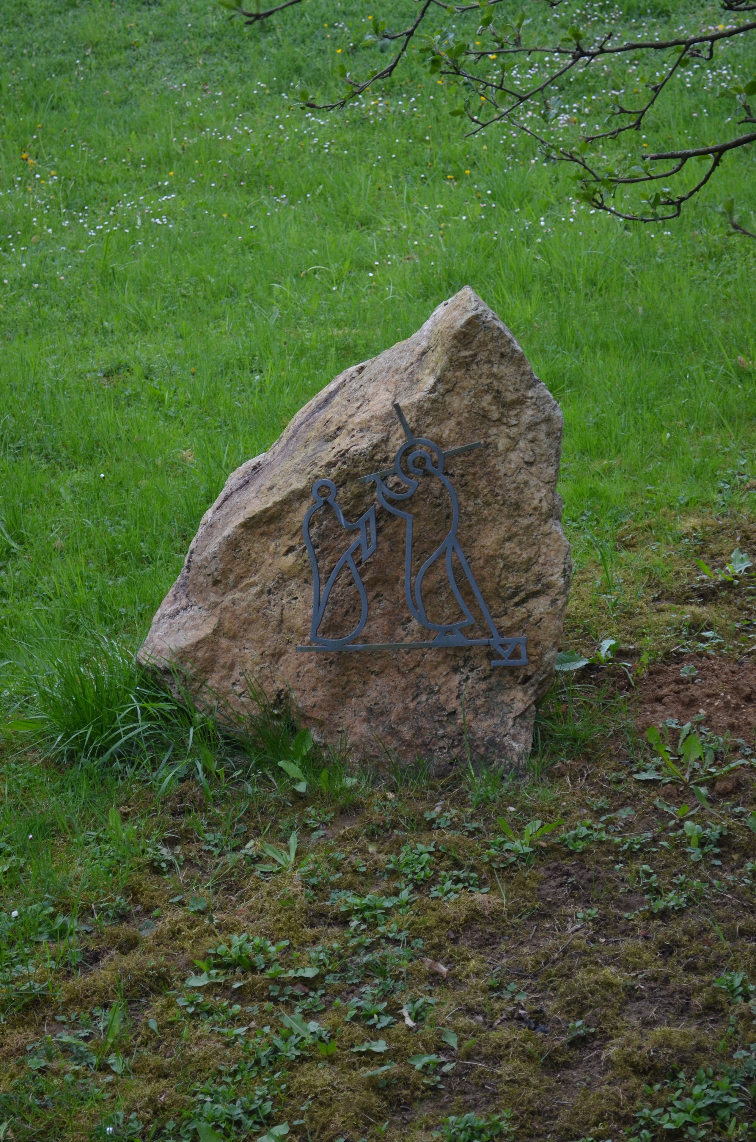 A large rock with a metal sculpture of a person riding a bicycle.