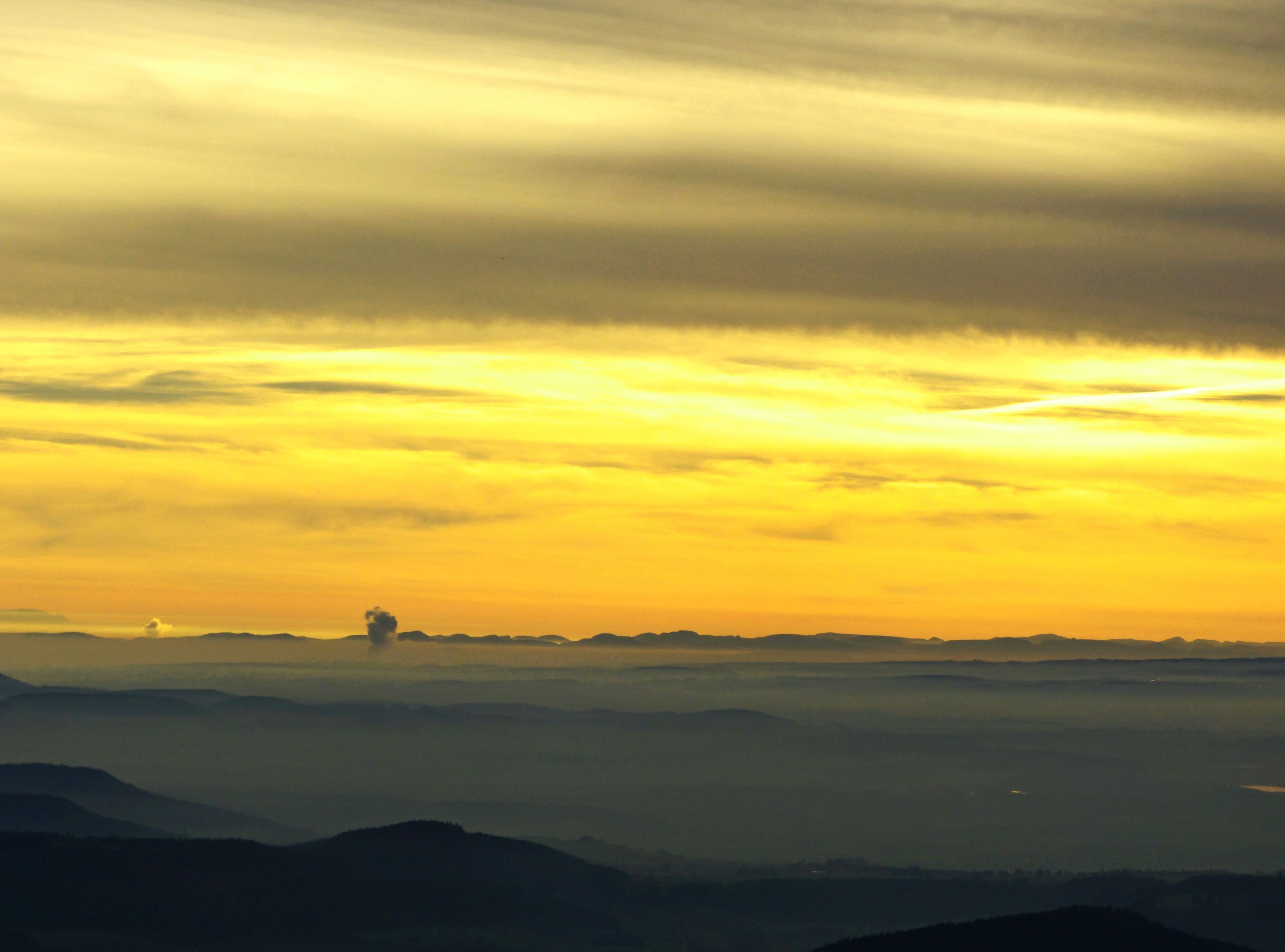 A sunset over a mountain range with clouds.