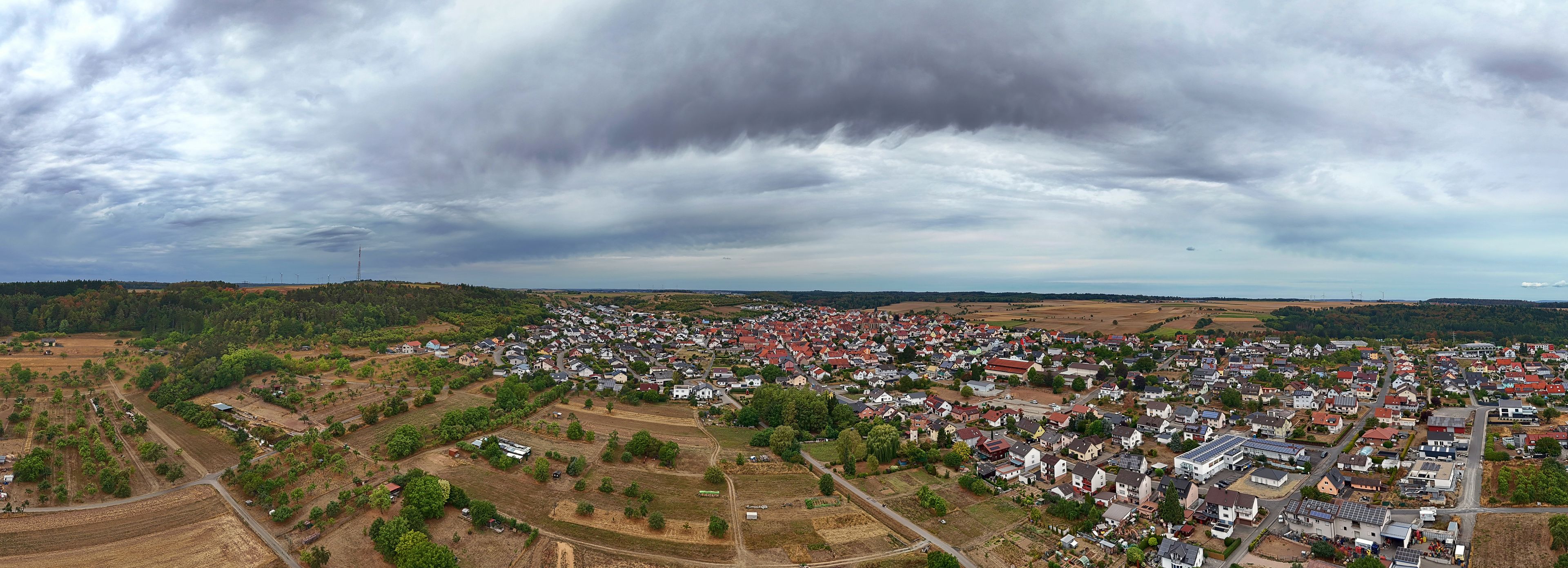 Un pueblo con una combinación de viviendas y campos de cultivo, bajo un cielo nublado.