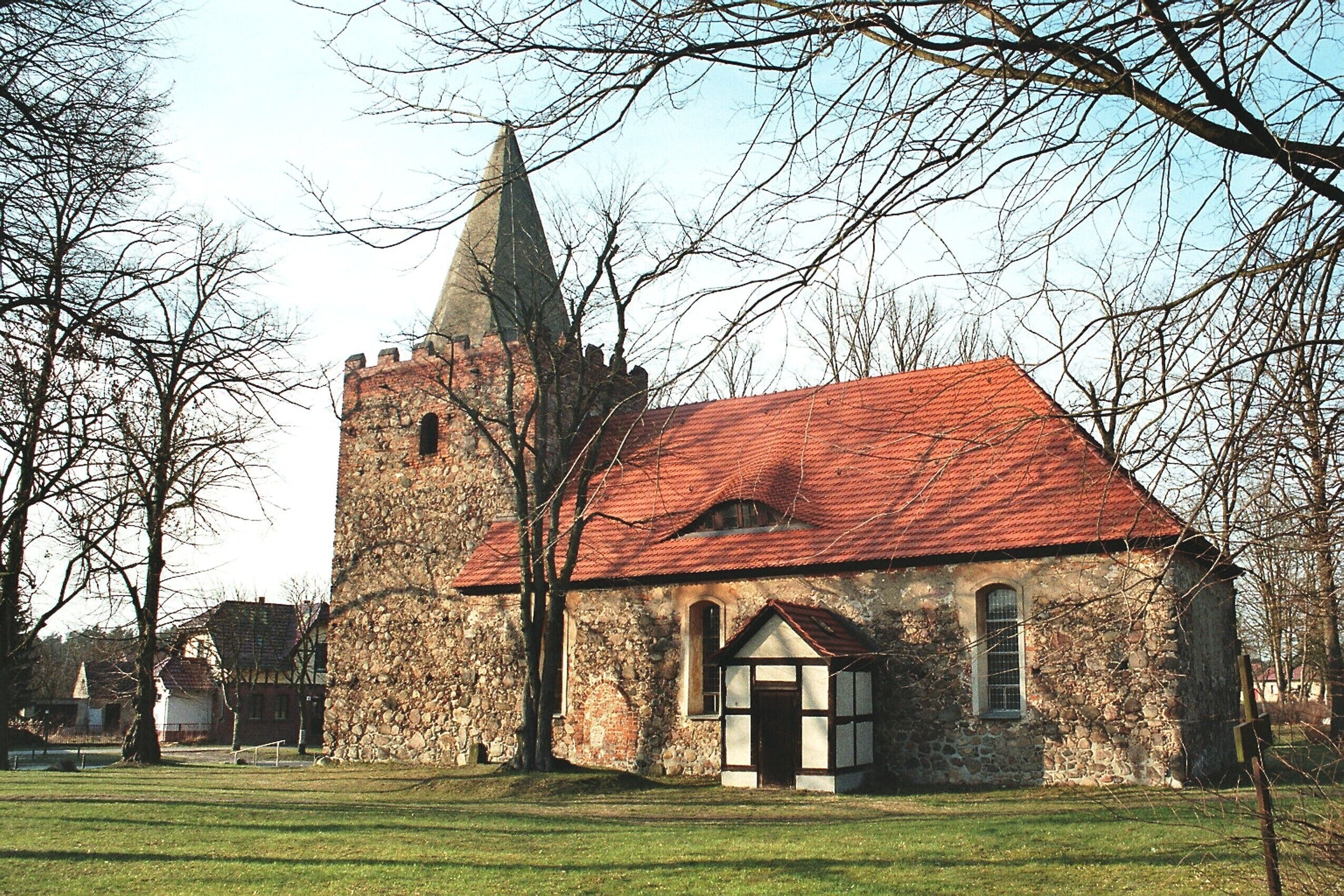 A historic stone church with a red roof and a tall tower.
