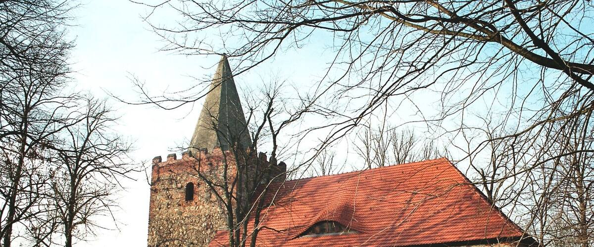 A historic stone church with a red roof and a tall tower.