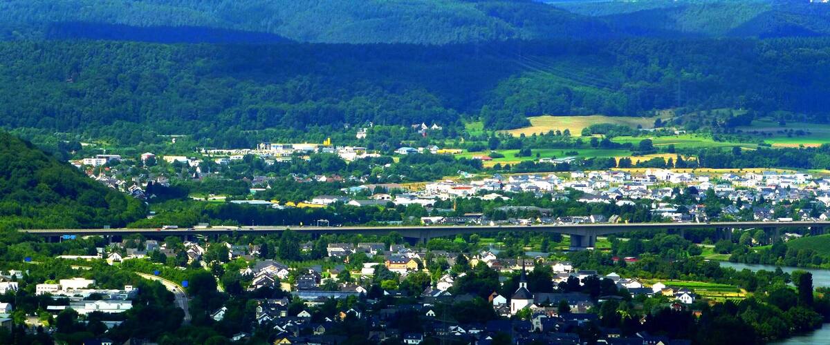 A river flowing through a town surrounded by hills and greenery.