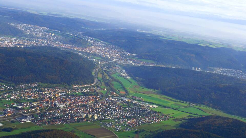 An aerial view of a town nestled in a valley with surrounding hills and fields.