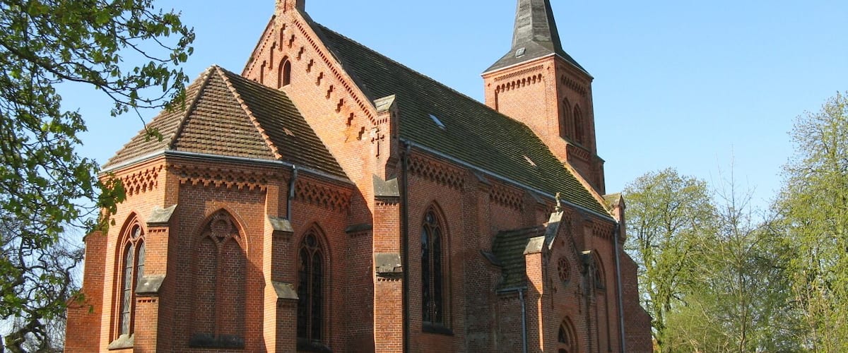 A brick church with a tall steeple and arched windows.