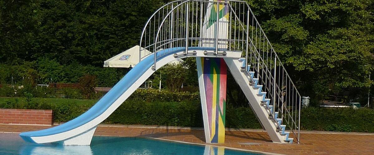 A swimming pool with a blue slide and a colorful staircase.