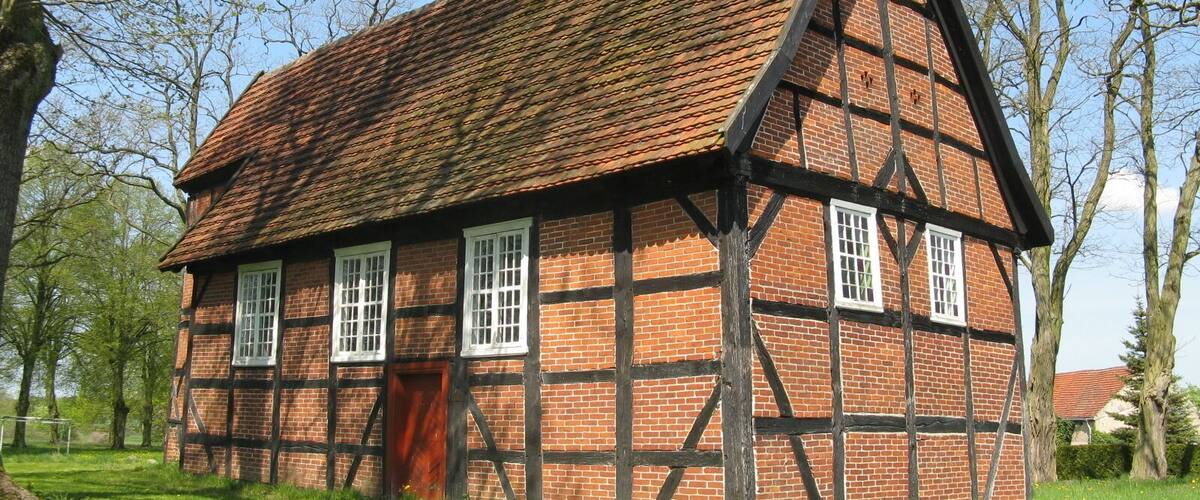 A traditional half-timbered house with a steeply pitched roof and a red door.