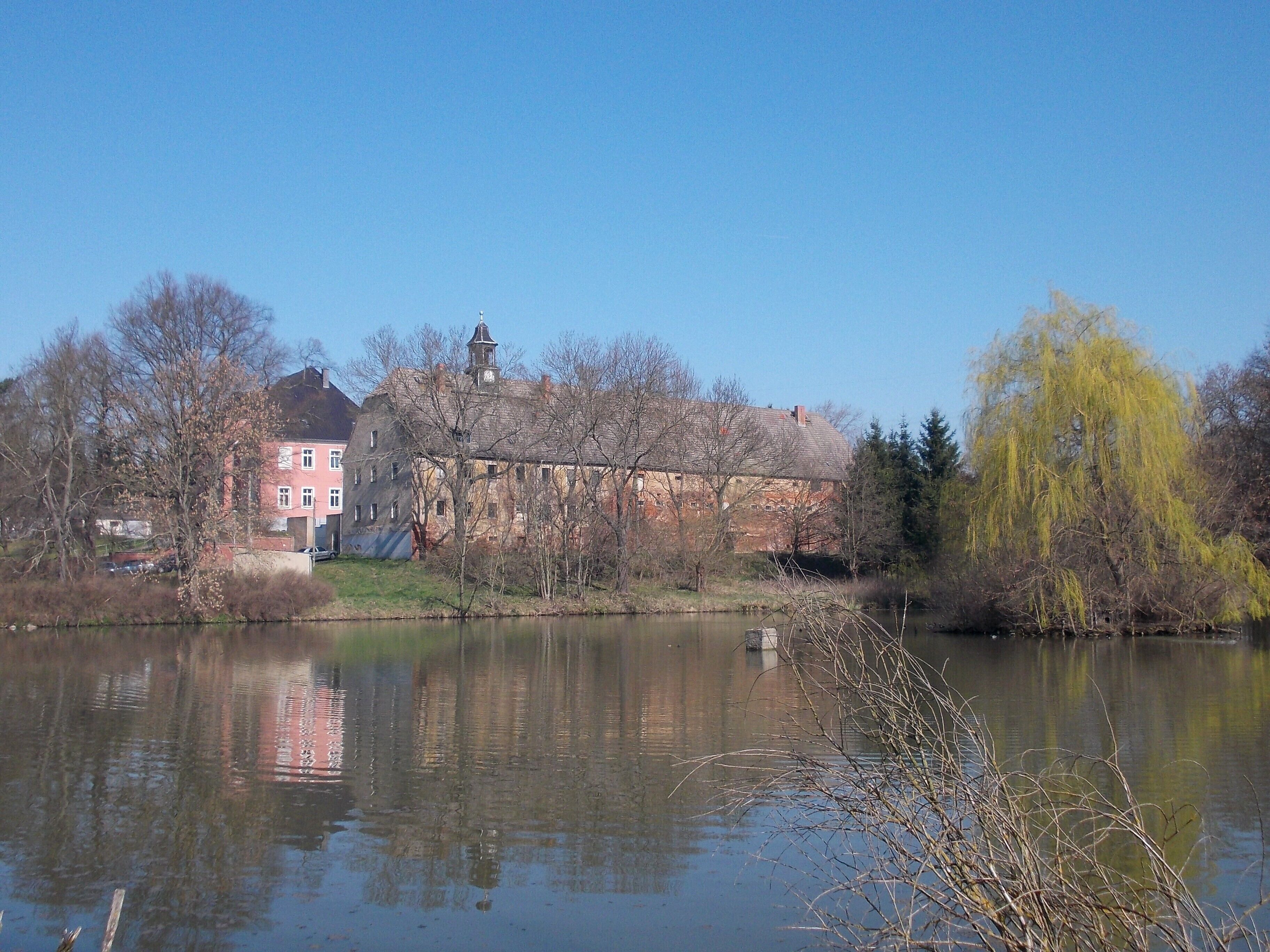 A calm river with reflections of buildings and trees.