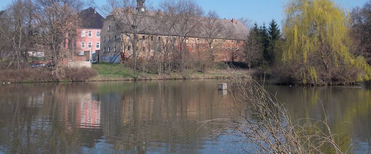 A calm river with reflections of buildings and trees.