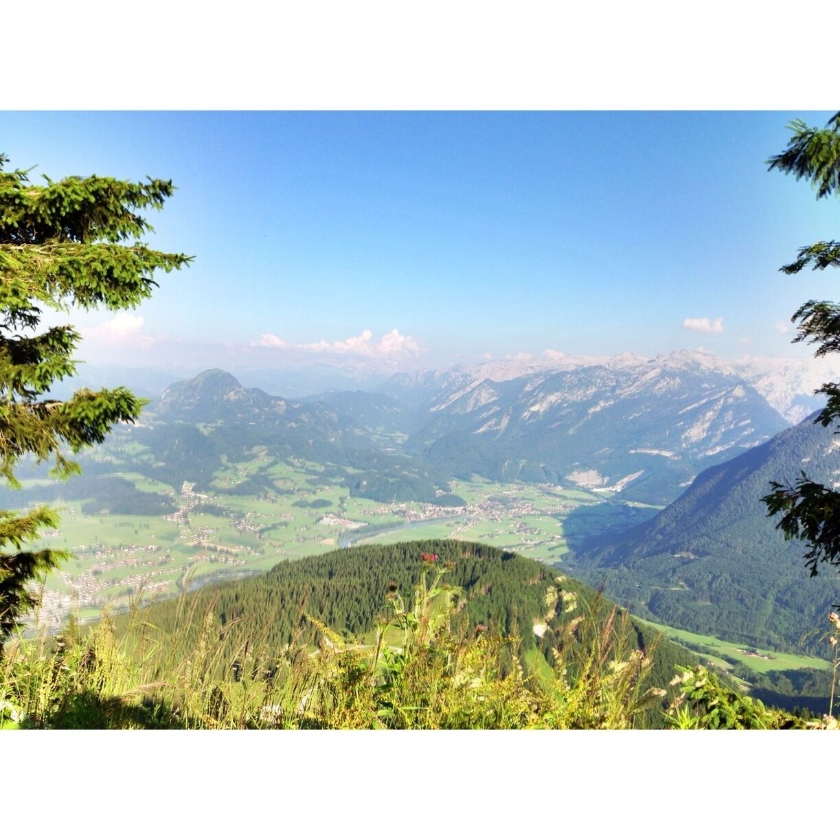 A mountainous landscape with a valley, forested areas, and a small town.