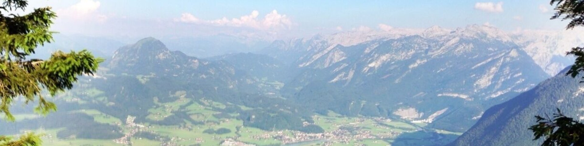 A mountainous landscape with a valley, forested areas, and a small town.