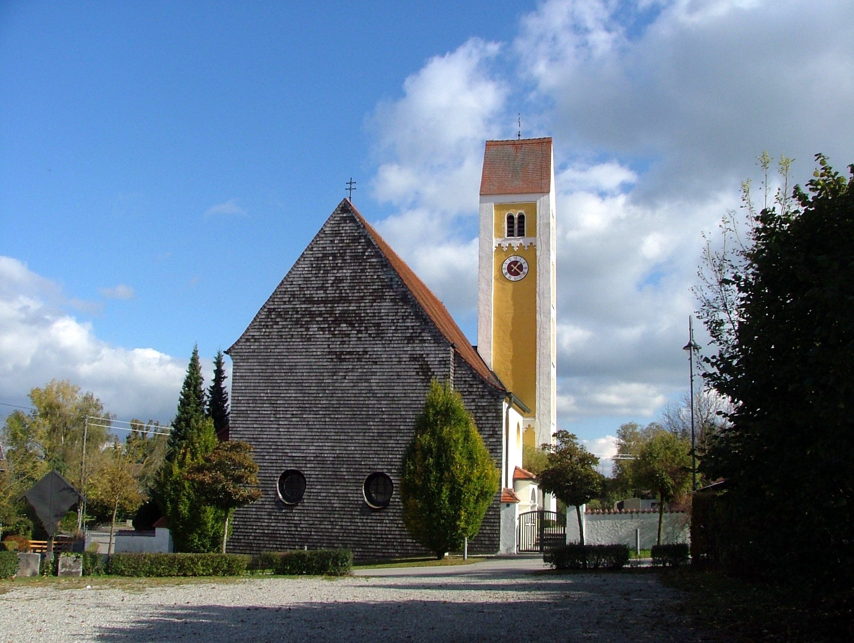 A church with a tall bell tower and a wooden building with circular windows.