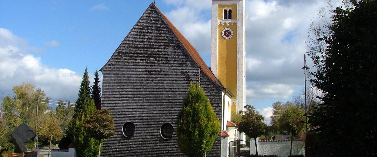A church with a tall bell tower and a wooden building with circular windows.