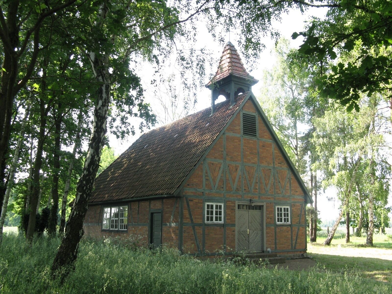 A traditional half-timbered building with a steeply pitched roof and a small tower.