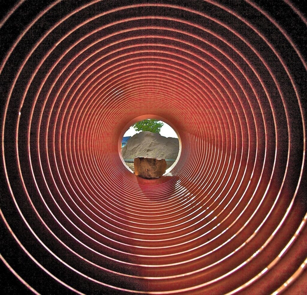 A circular tunnel with concentric red lines and a central rock formation.