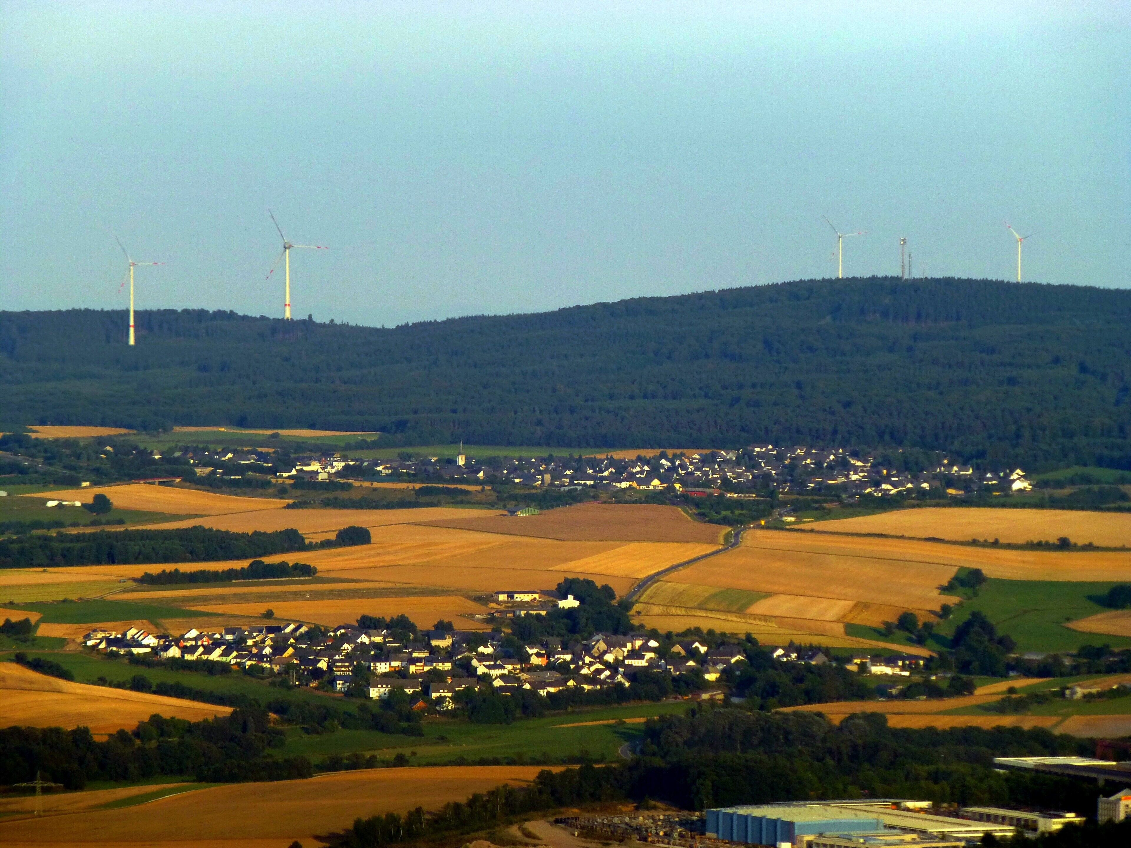 A rural landscape with wind turbines, a village, and fields.