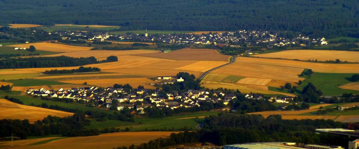 A rural landscape with wind turbines, a village, and fields.