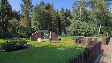 Un parco con una panchina di legno, una costruzione in mattoni e un'area recintata.