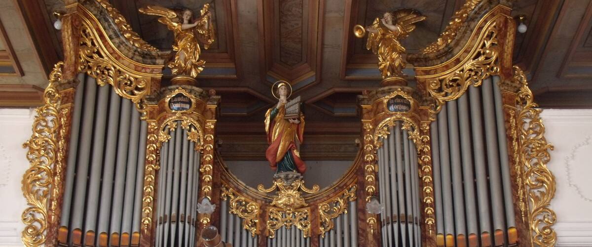 An ornate organ with gold accents and statues.