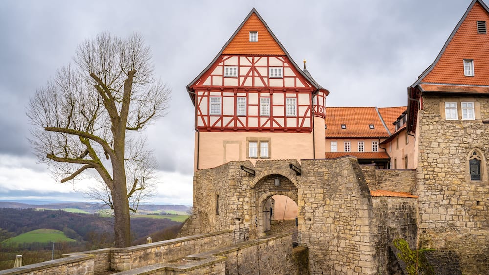 A historic castle with a stone wall and a red-tiled roof.