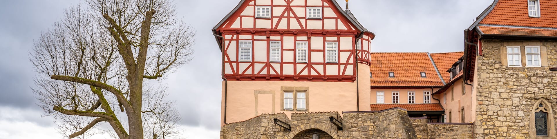 A historic castle with a stone wall and a red-tiled roof.