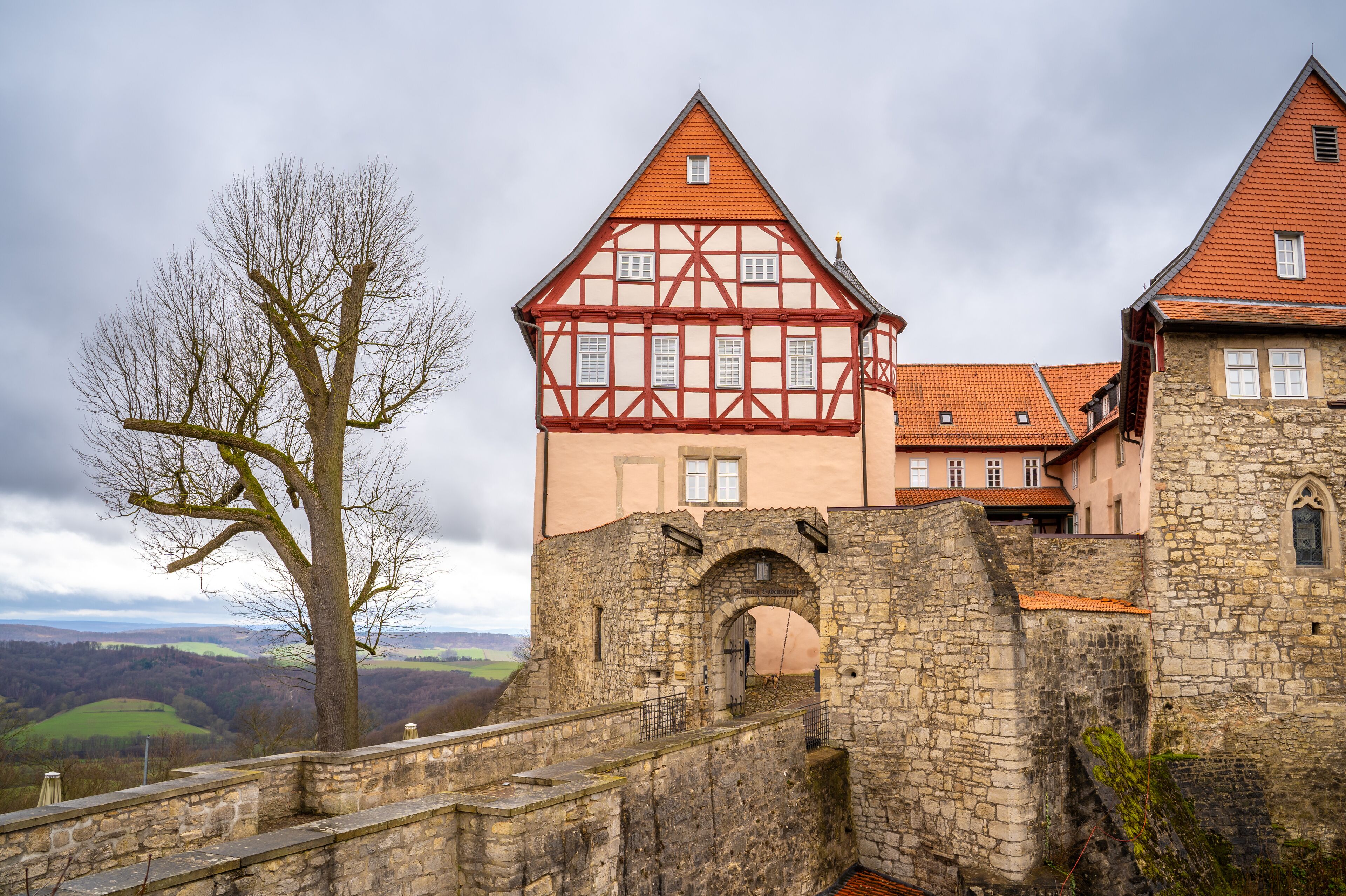 A historic castle with a stone wall and a red-tiled roof.