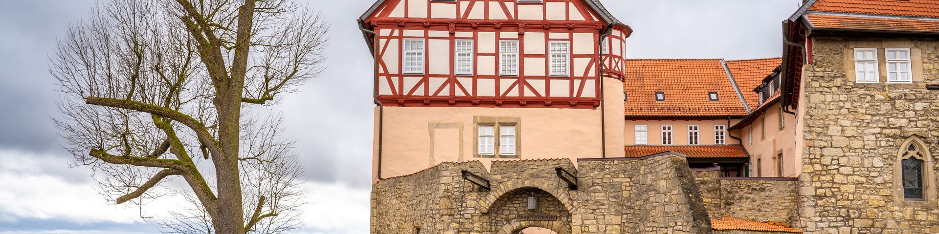 A historic castle with a stone wall and a red-tiled roof.