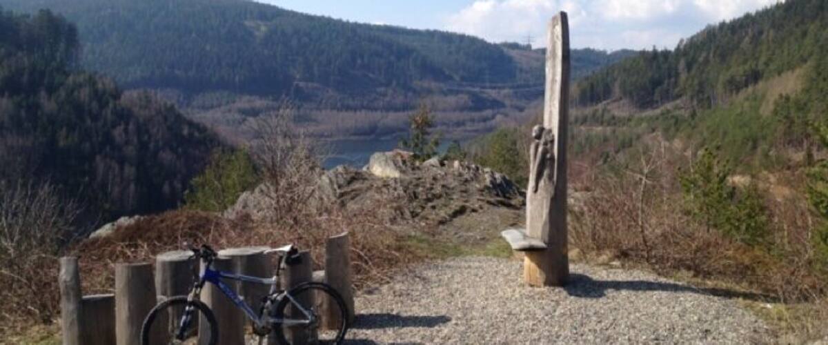 A mountain landscape with a bicycle parked near a wooden post.