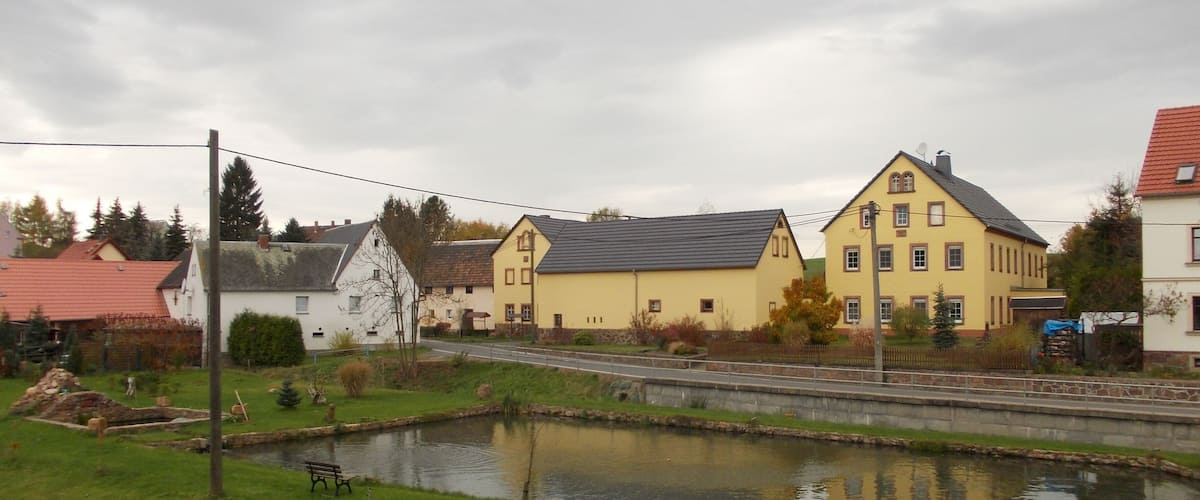A small pond surrounded by houses with a cloudy sky.